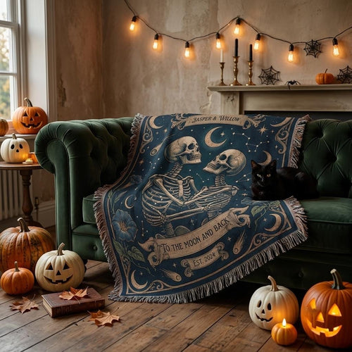Navy skeleton couple throw draped over a green velvet sofa with a black cat and carved pumpkins