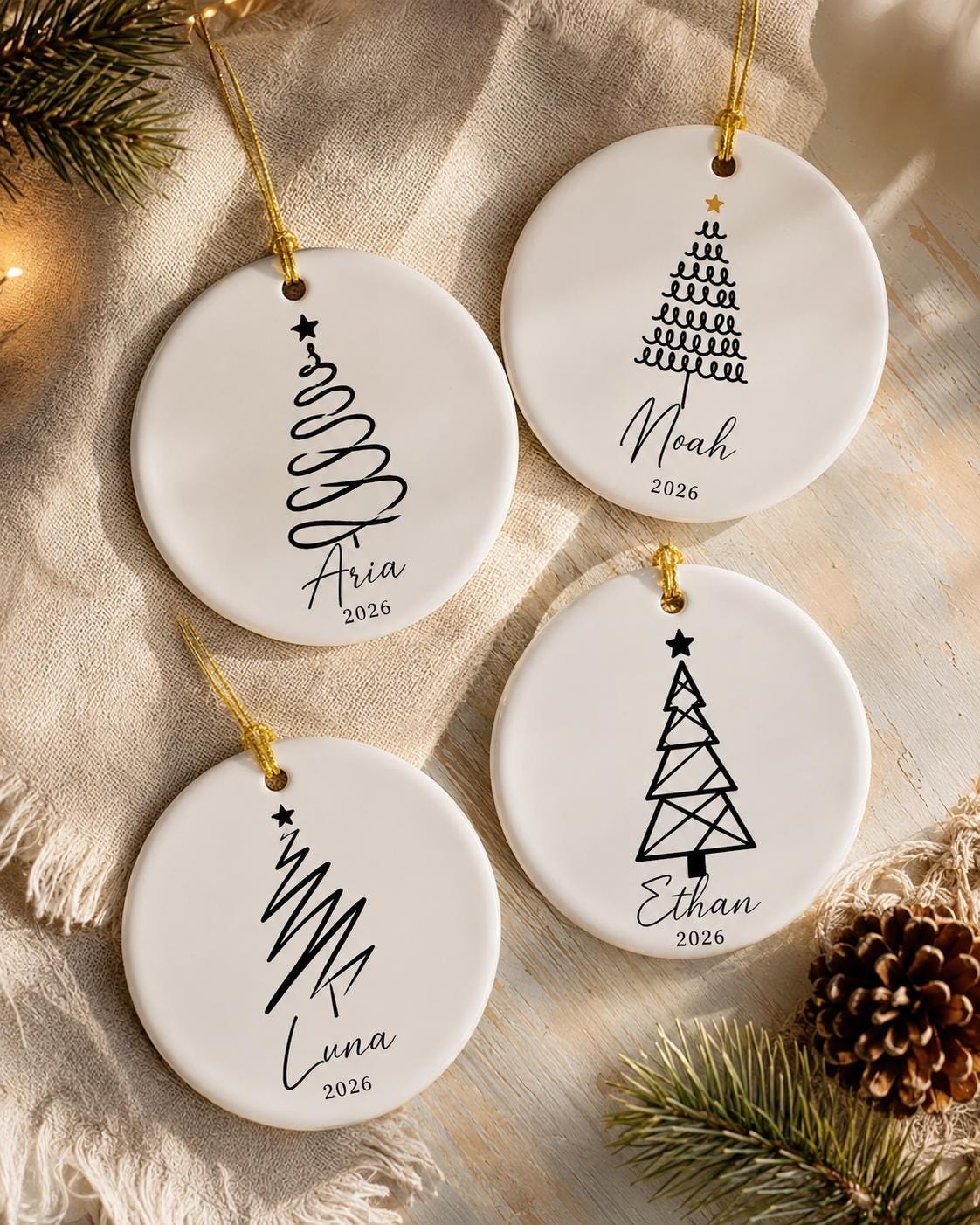 Four round minimalist tree ornaments personalized with Aria, Noah, Luna and Ethan on a cream throw