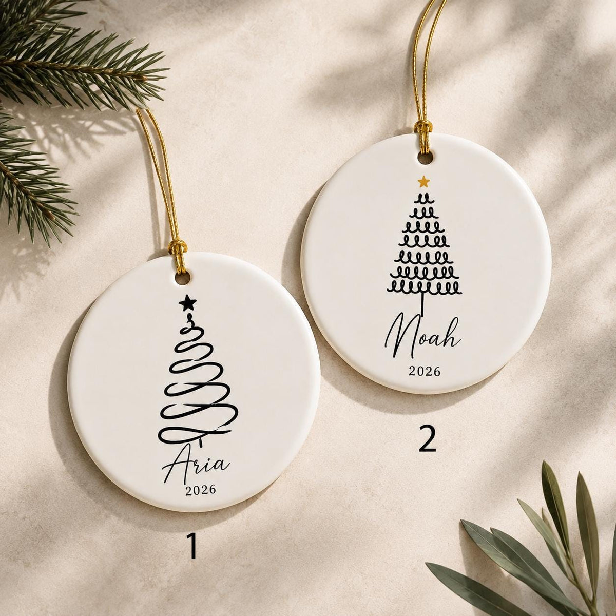 Two round ceramic ornaments showing tree designs 1 and 2 with the names Aria and Noah