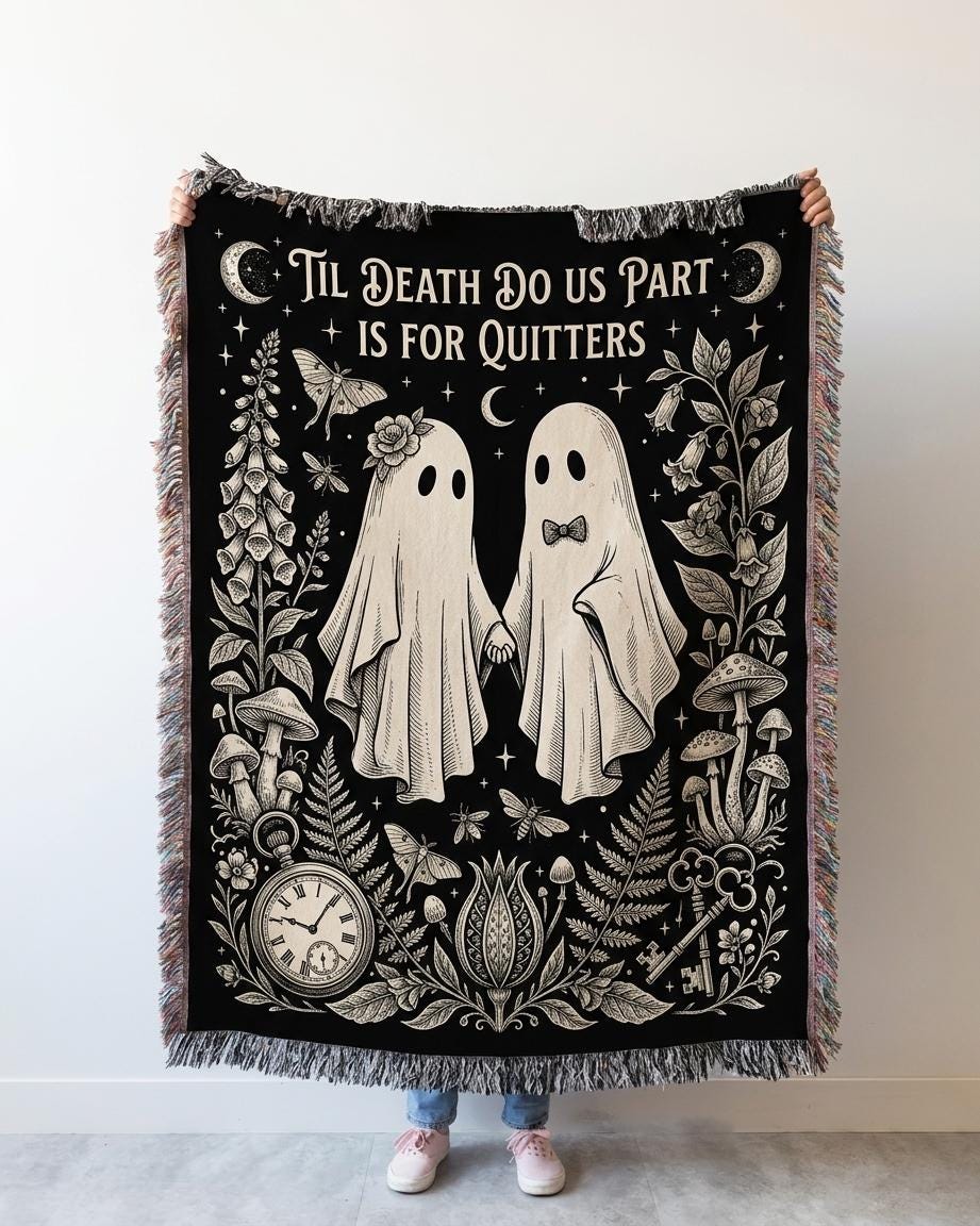Person holding up the black and cream ghost couple woven blanket against a white wall