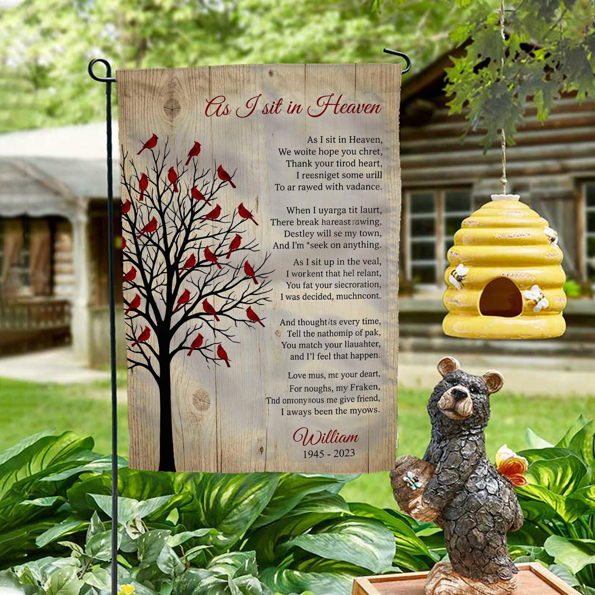 As I Sit In Heaven cardinal tree poem memorial garden flag with name on a garden stand by a log cabin with a beehive and bear statue