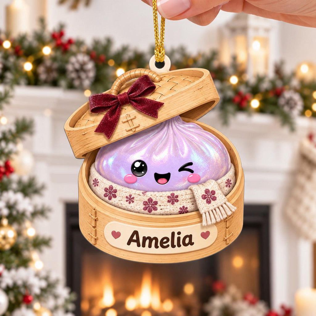 Hand holding a lavender bao dumpling steamer ornament with a red bow by the fireplace