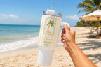 40oz handle tumbler with a palm tree stamp design held on the beach