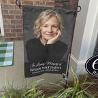 Black In Loving Memory portrait garden flag with name and dates on a stand by a brick front porch