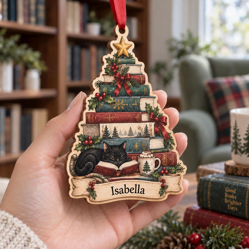 Hand holding a book stack Christmas tree ornament with sleeping black cat