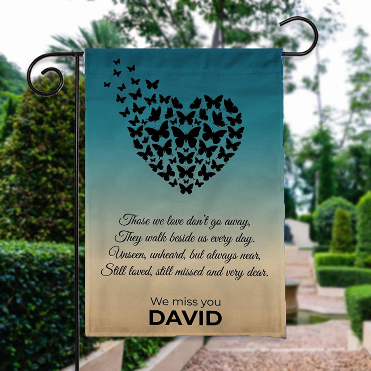 Butterfly heart Those We Love Don't Go Away memorial garden flag beside a stone garden path