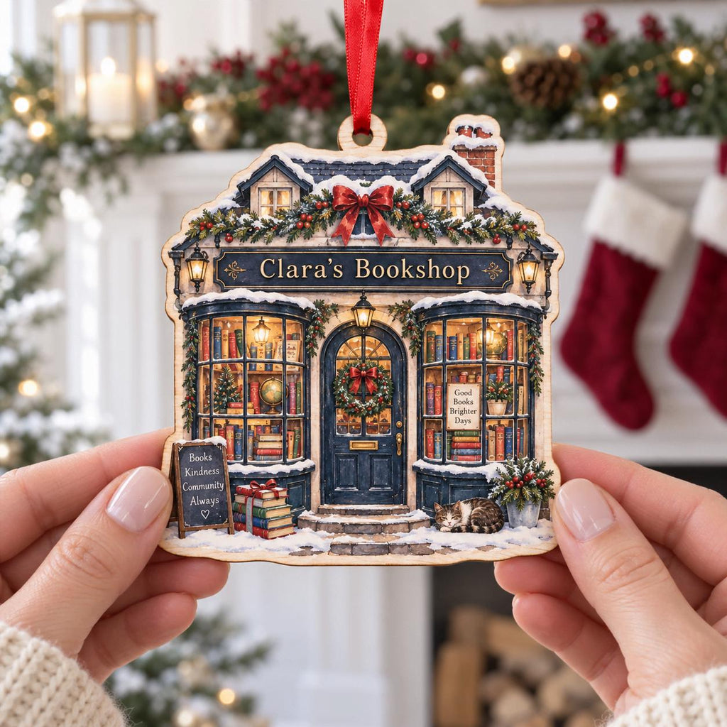 Hands holding a personalized Christmas bookshop ornament named Clara's Bookshop