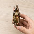 Hand holding the flower shop wooden ornament sideways to show its flat thickness