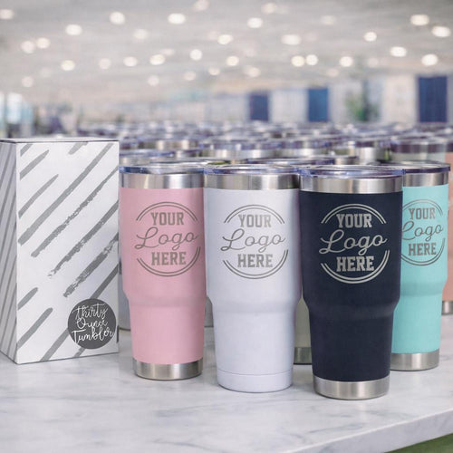 Pink, white, navy and turquoise 30oz tumblers engraved with a logo, next to a gift box