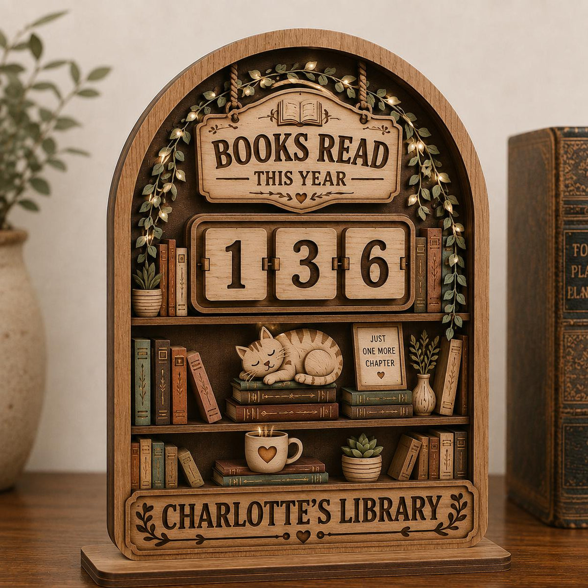 Cozy cat library book tracker with Charlotte's Library name plate on a shelf beside an old hardcover book