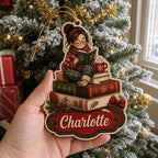 Hand holding personalized reading girl wooden ornament near frosted Christmas tree and gifts