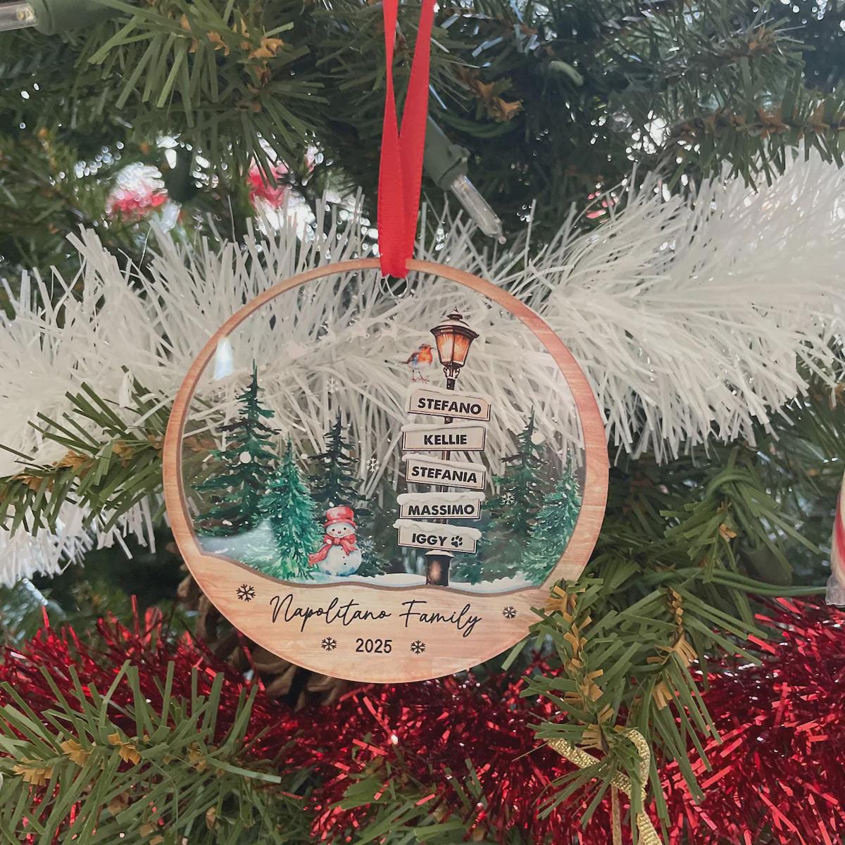 Personalized family names ornament hanging on a snowy garland