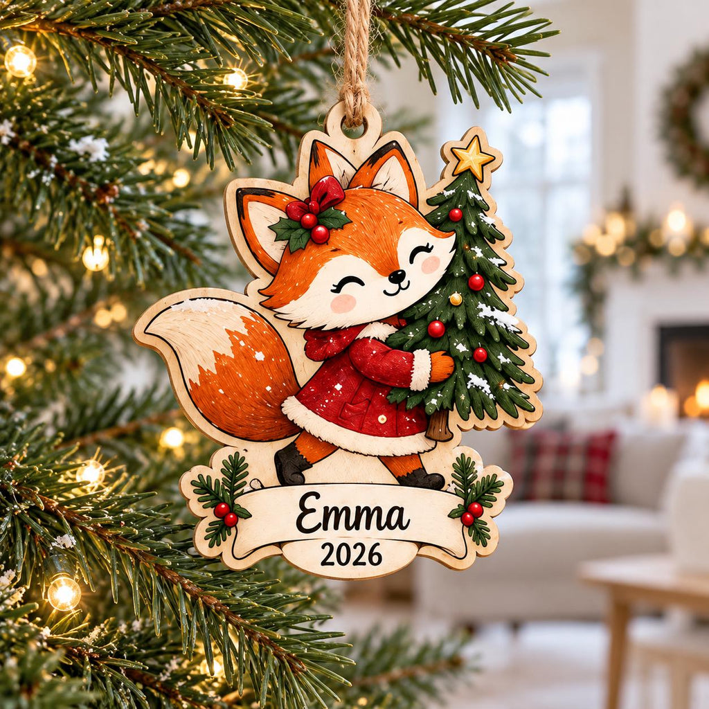 Fox carrying a Christmas tree wooden ornament with name Emma hanging on a tree