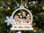 Gingerbread family ornament with a plaid bow on a lit Christmas tree