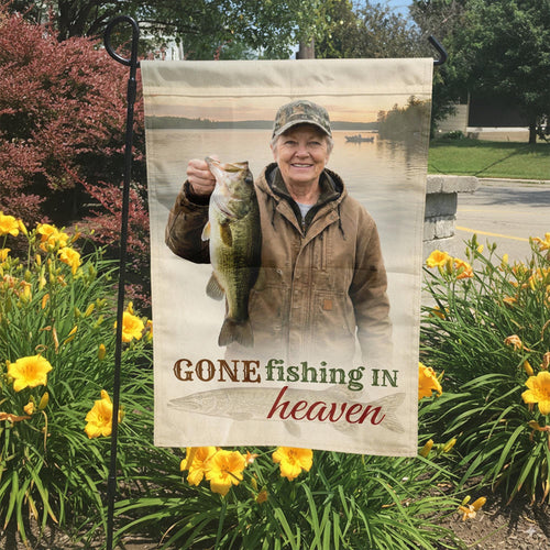 Gone Fishing In Heaven photo memorial garden flag in a garden bed with yellow lilies