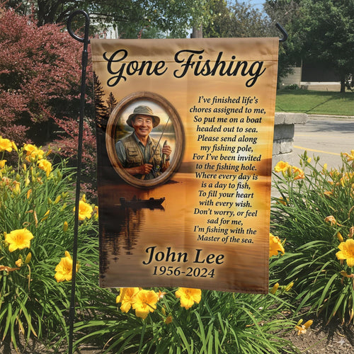 Gone Fishing lake sunset photo memorial garden flag with poem, name and years in a garden bed with yellow lilies