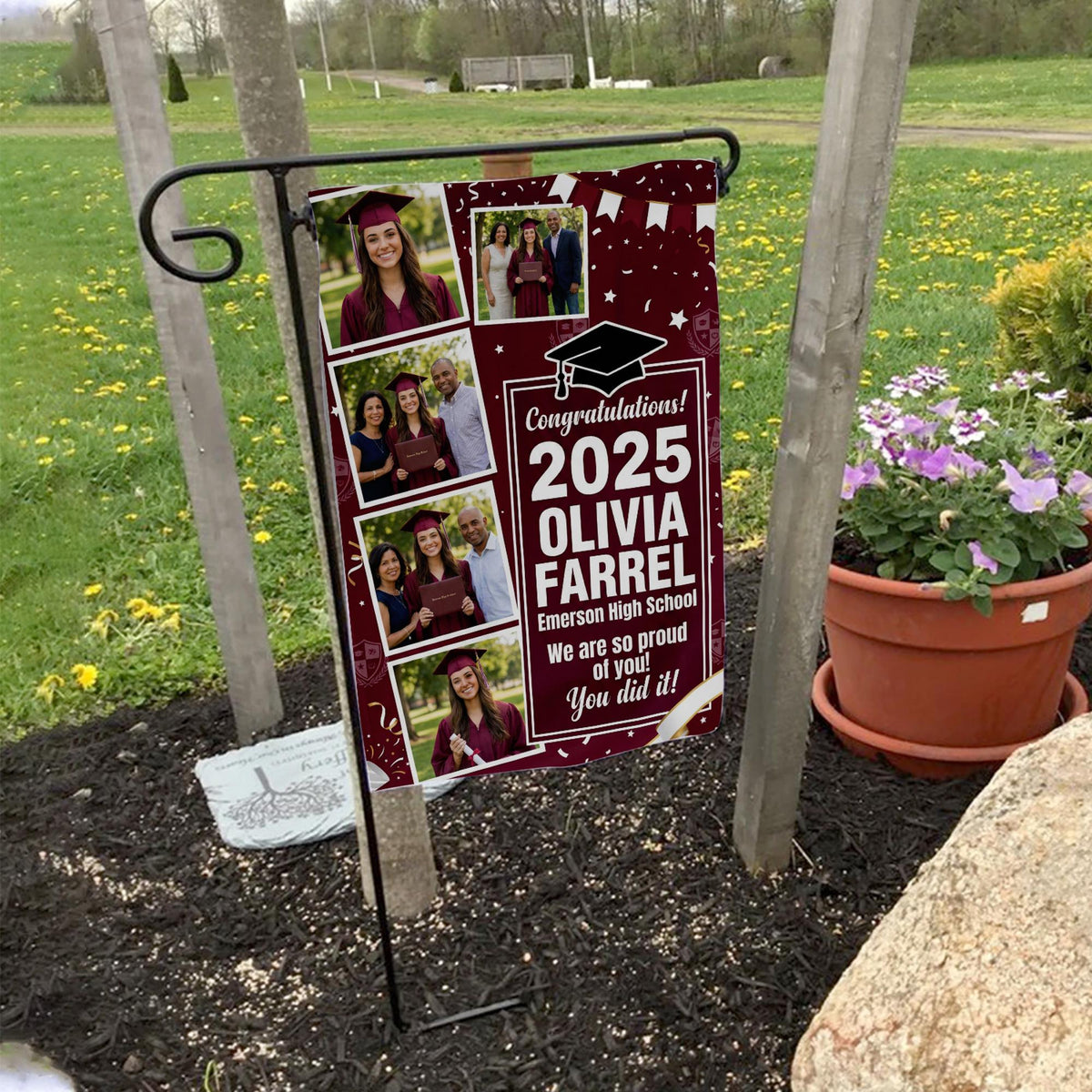 Maroon graduation photo collage garden flag with grad year, name and school on a garden flag stand in a yard with potted flowers