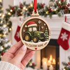 Hand holding a personalized round green tractor wooden ornament with Santa hat and name