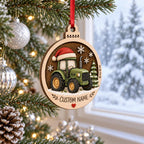Green tractor round wooden ornament with snowflakes and name by a snowy window
