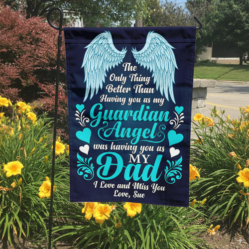 Guardian Angel Dad teal angel wings memorial garden flag in a garden bed with yellow lilies