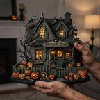 Hands holding a personalized moss-green haunted house with jack-o'-lanterns, in a living room near a fireplace