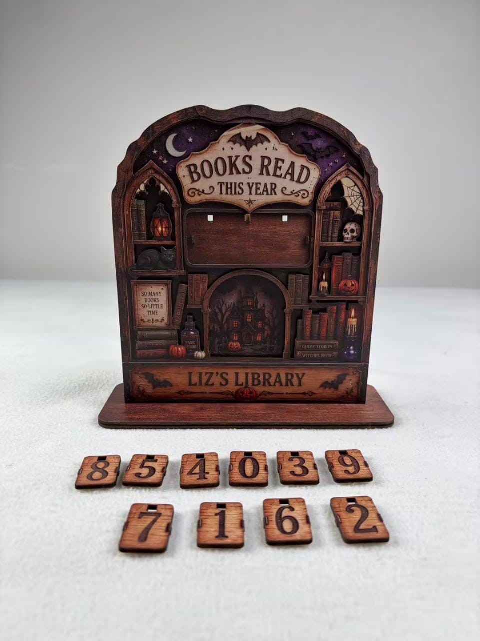 Real photo of the haunted house book tracker reading Liz's Library, with loose wooden number cards in front