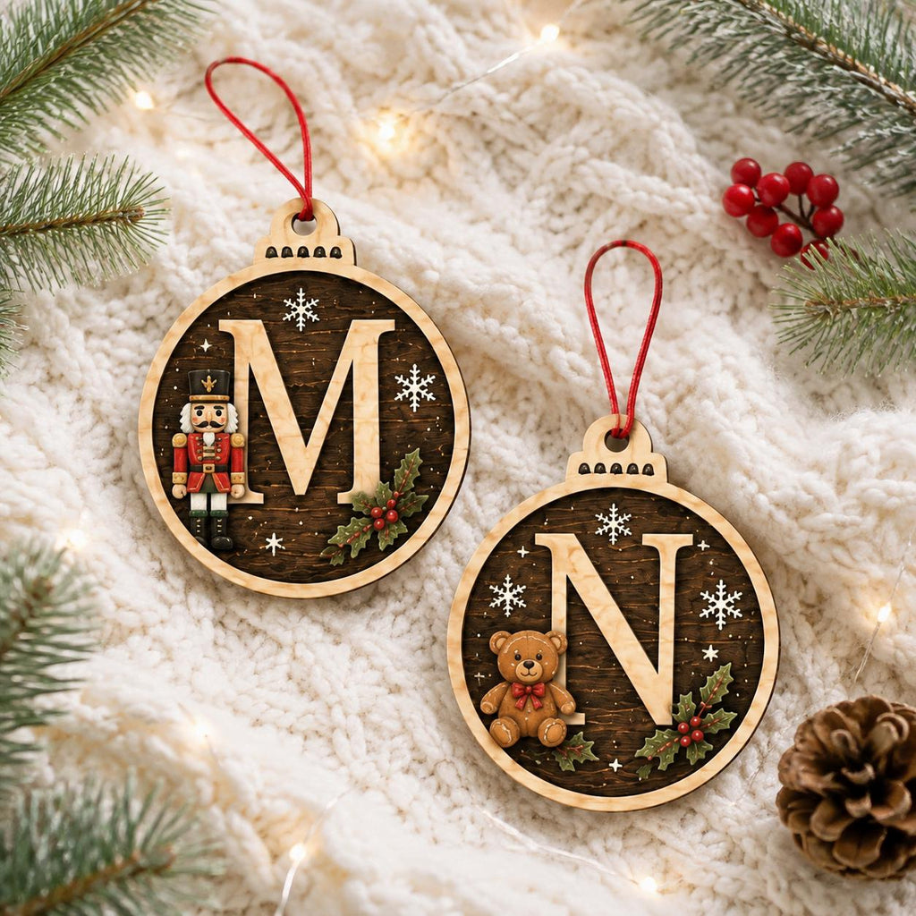 Nutcracker M and teddy bear N dark round initial ornaments on a knit blanket