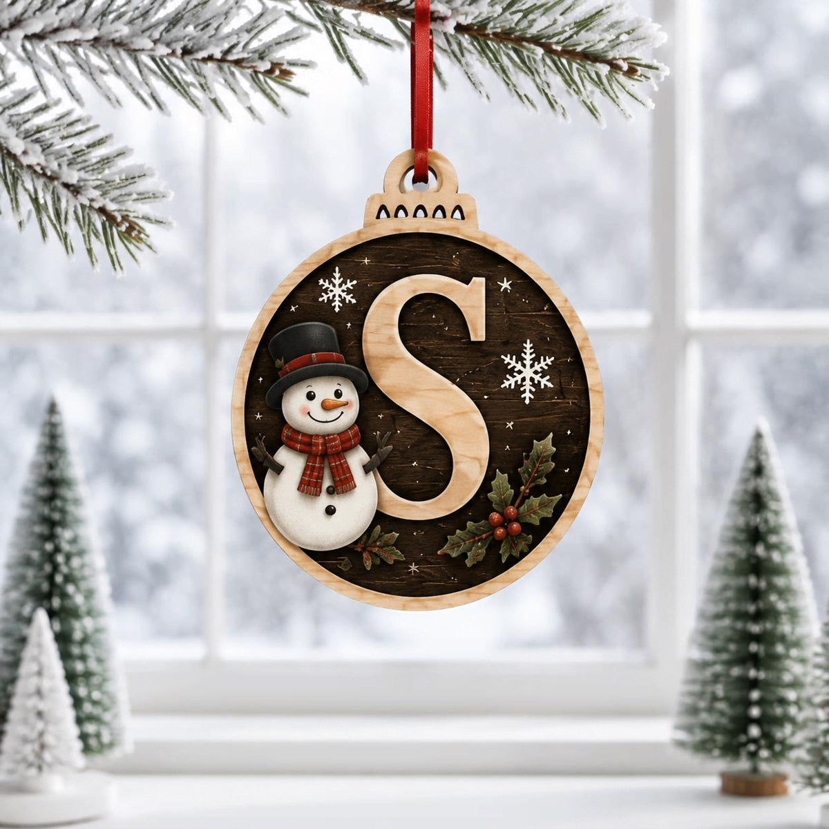 Snowman letter S dark round monogram ornament hanging by a snowy window