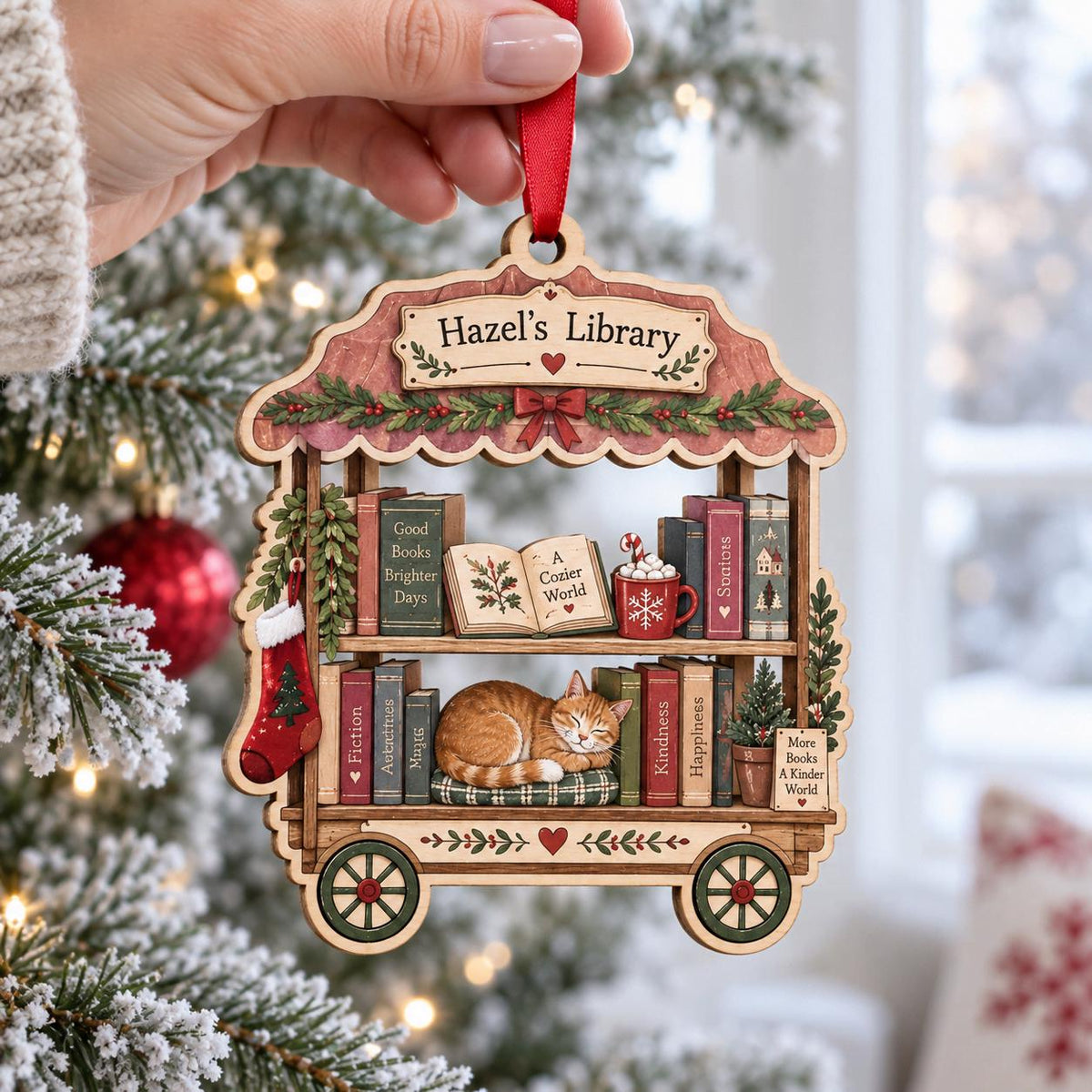 Wooden library cart bookshelf ornament with sleeping cat on a snowy Christmas tree