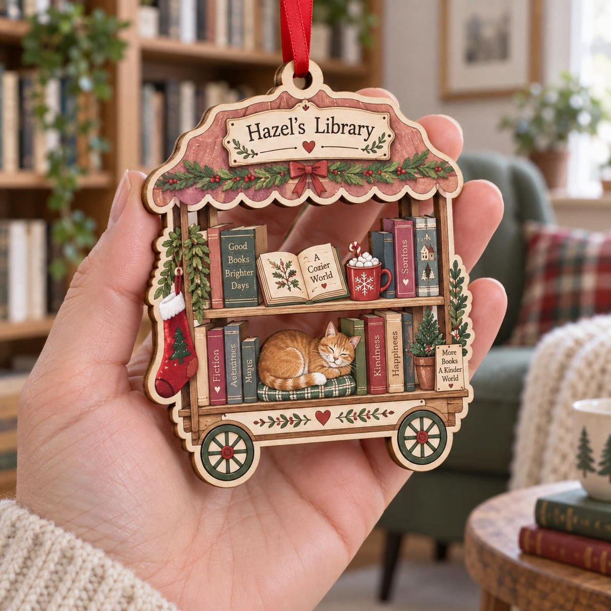 Hand holding a personalized library cart ornament with books and orange cat