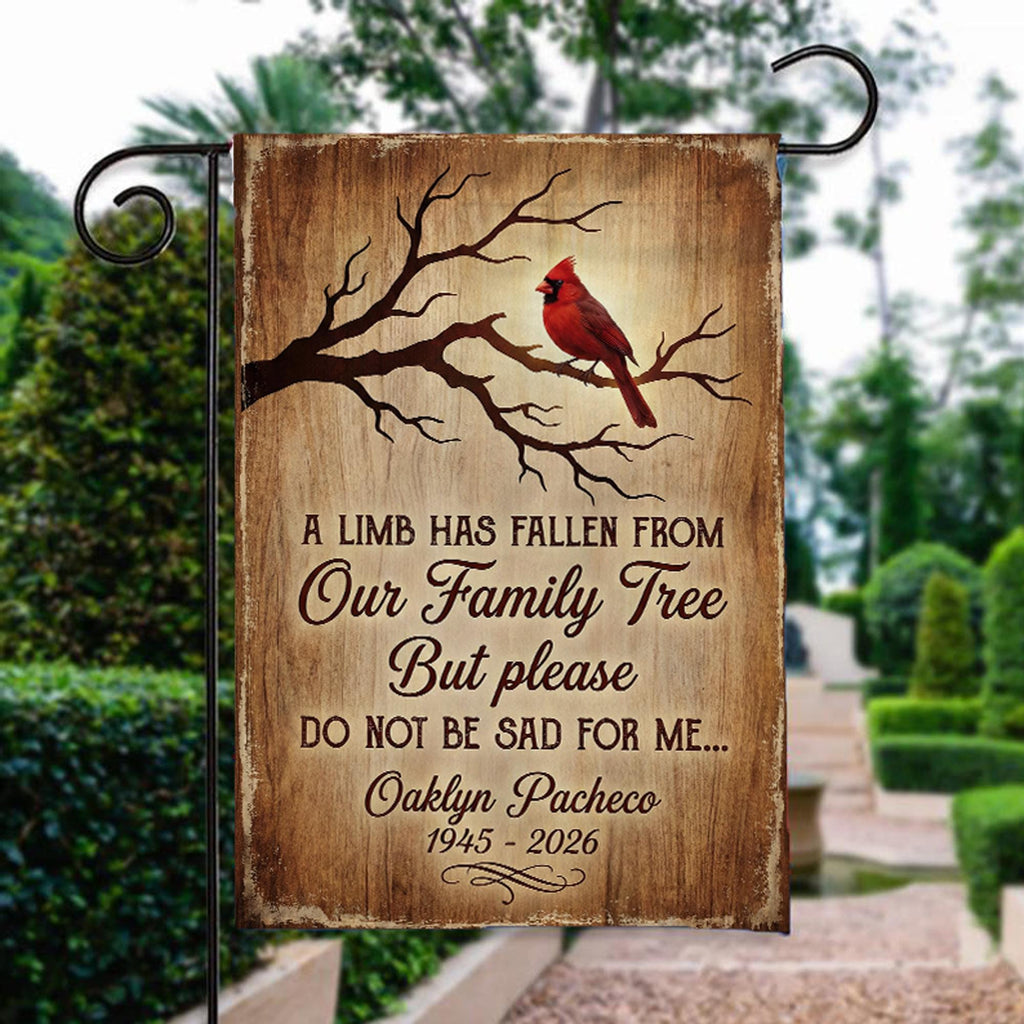 A Limb Has Fallen cardinal memorial garden flag with name and years beside a stone garden path