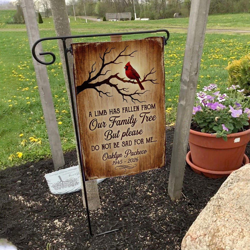 A Limb Has Fallen cardinal memorial garden flag with name and years on a garden flag stand in a yard with potted flowers