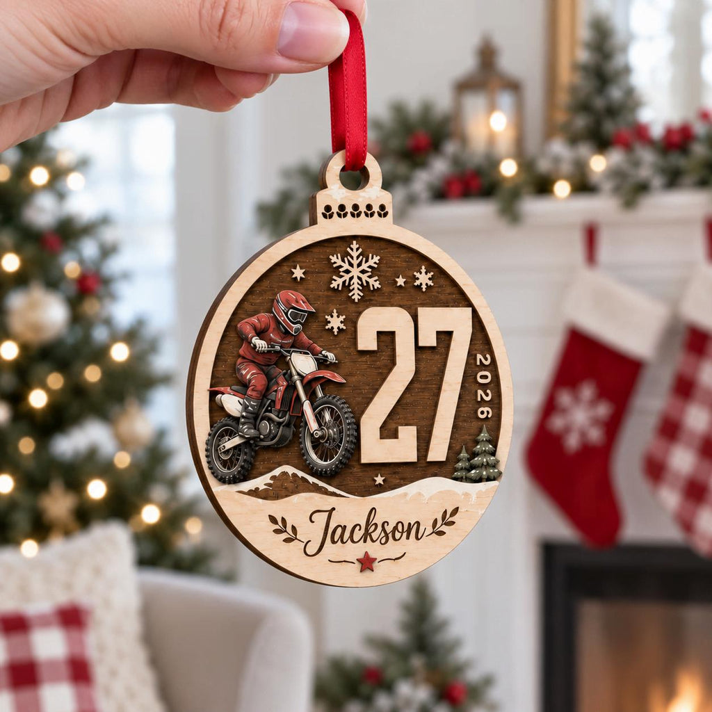 Hand holding a round motocross dirt bike wooden ornament with race number and name
