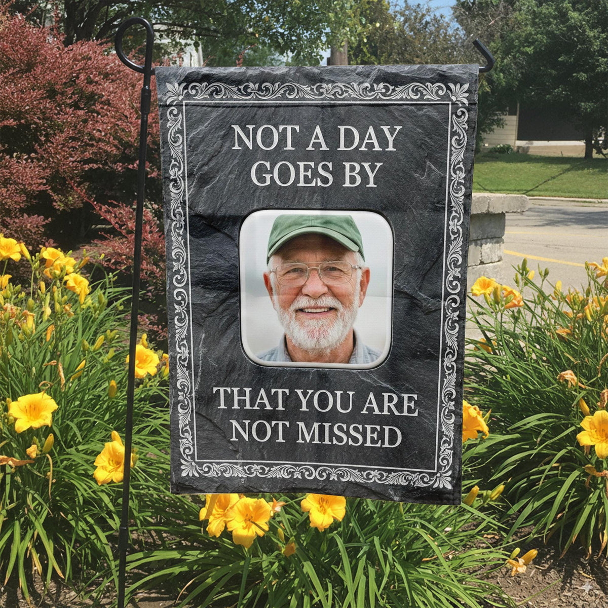 Not A Day Goes By slate style photo memorial garden flag in a garden bed with yellow lilies