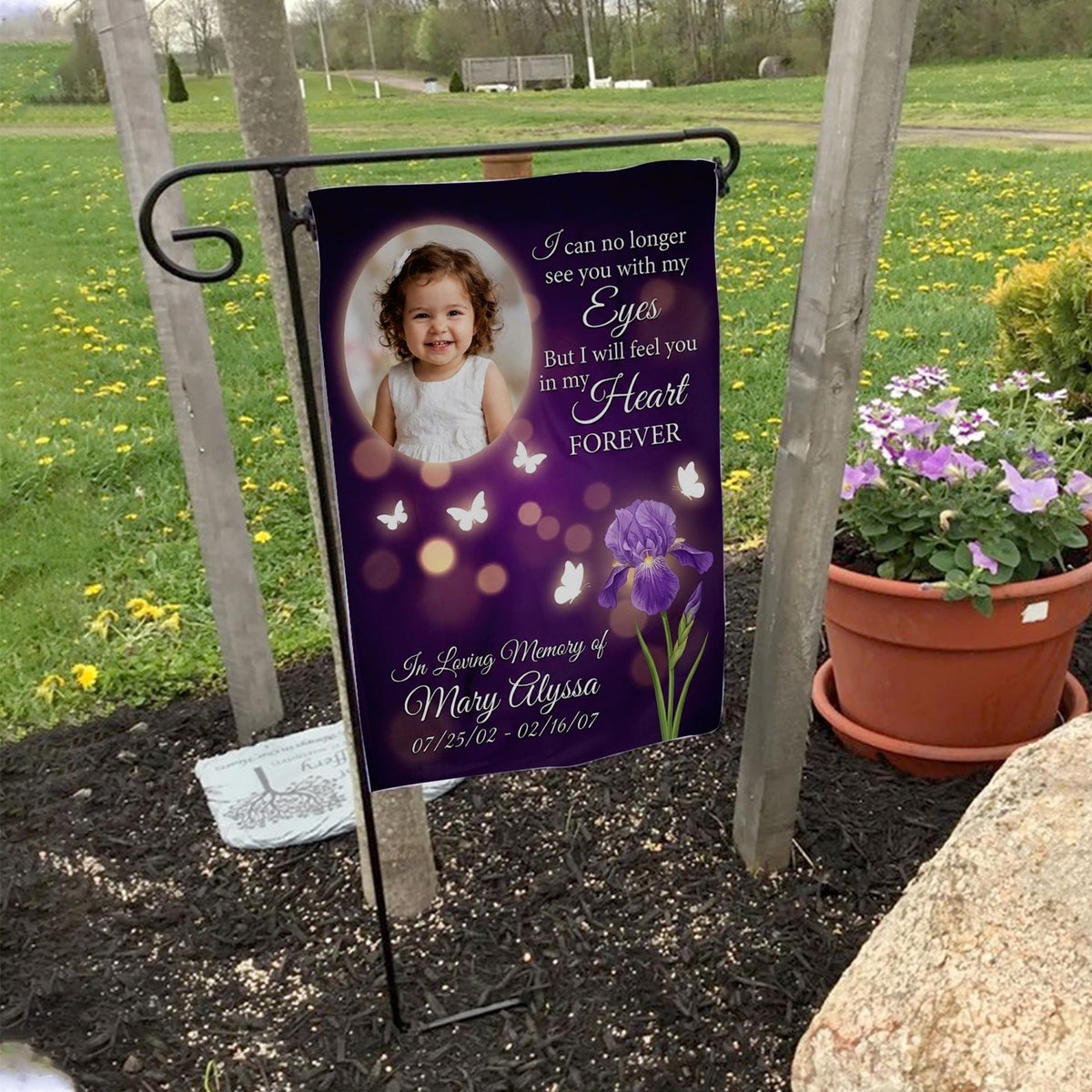 Purple iris and butterfly photo memorial garden flag with name and dates on a garden flag stand in a yard with potted flowers