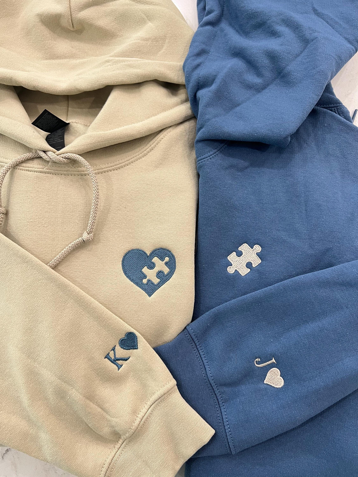 Close view of the heart and puzzle piece couple hoodies with sleeve initials