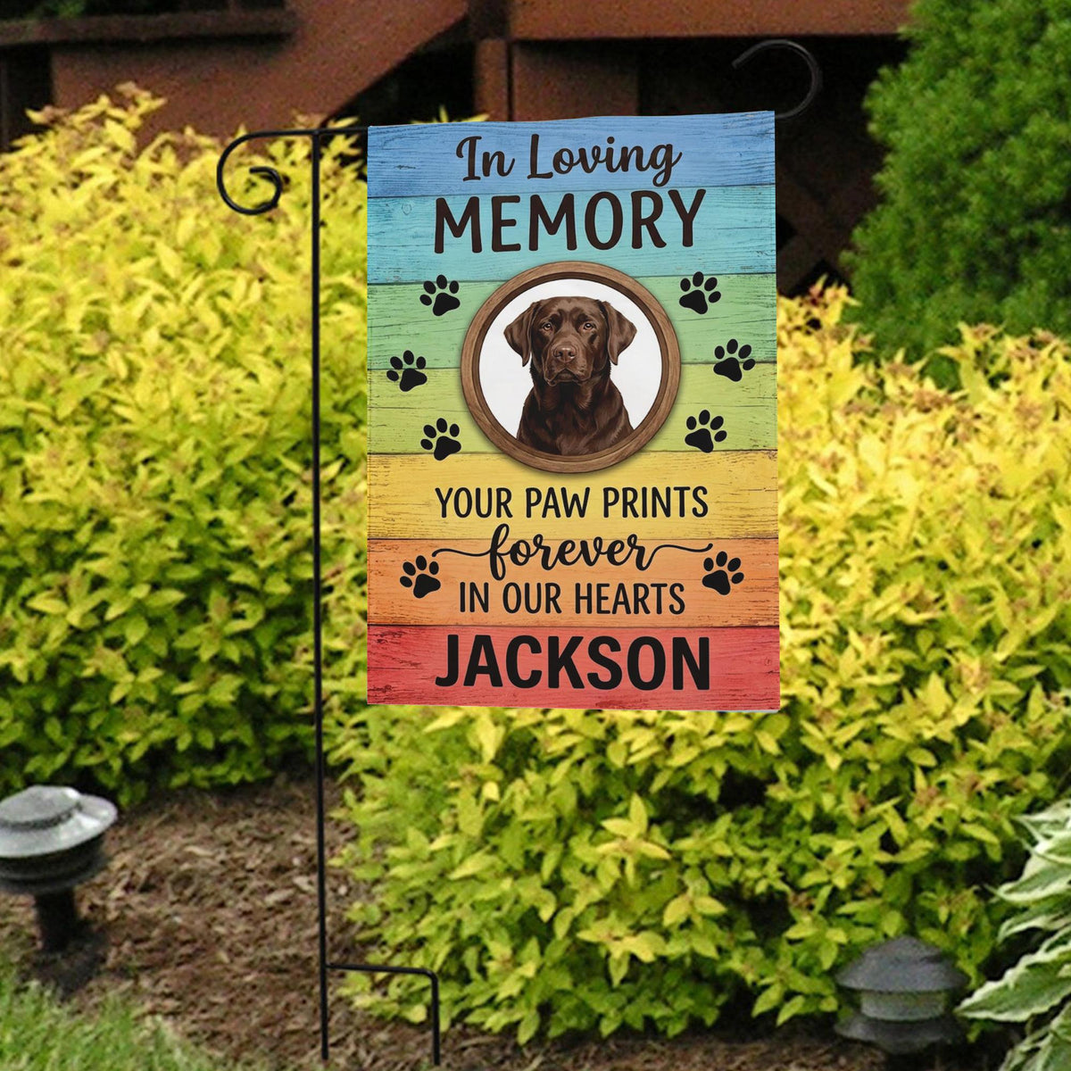 Rainbow Your Paw Prints Forever In Our Hearts dog memorial garden flag in front of bright yellow shrubs