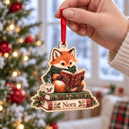Hand holding a personalized reading fox book stack ornament with name