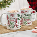Two white Christmas mugs printed with the name Rachel repeated in red and green fonts