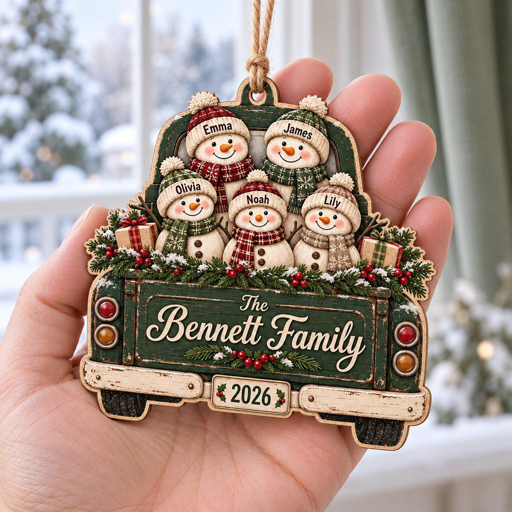 Hand holding a snowman family green truck wooden ornament with family name and year