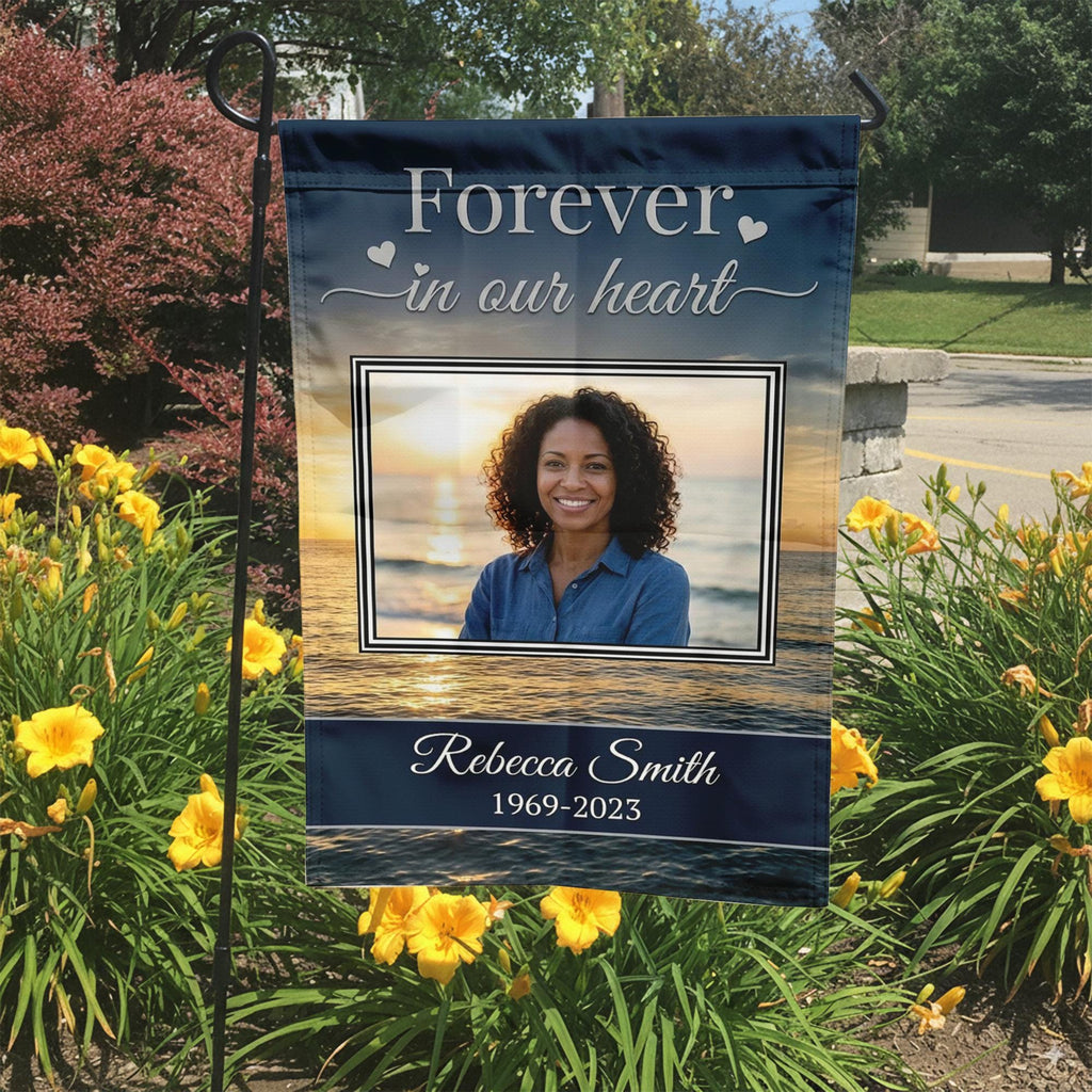 Forever In Our Heart sunset beach photo memorial garden flag with name and years in a garden bed with yellow lilies