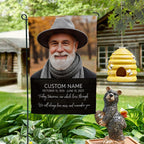 Today Tomorrow Always portrait memorial garden flag with name and dates on a garden stand by a log cabin with a beehive and bear statue