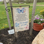 Too Beautiful For Earth butterfly baby memorial garden flag with name and dates on a garden flag stand in a yard with potted flowers