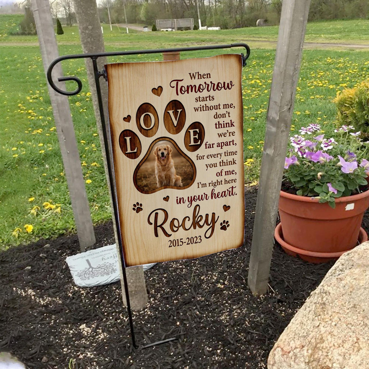 When Tomorrow Starts Without Me dog memorial garden flag with paw print photo on a garden flag stand in a yard with potted flowers